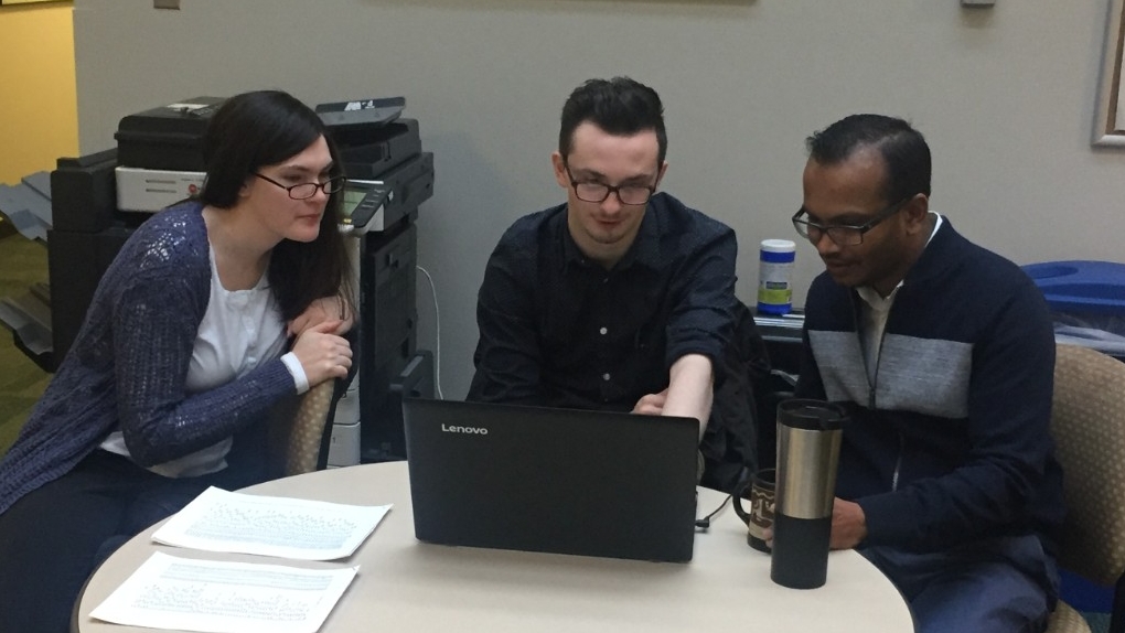 Three people sharing a laptop screen
